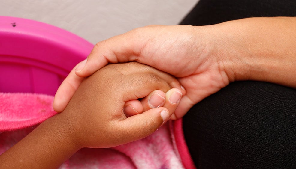 nurse holds young patient's hand